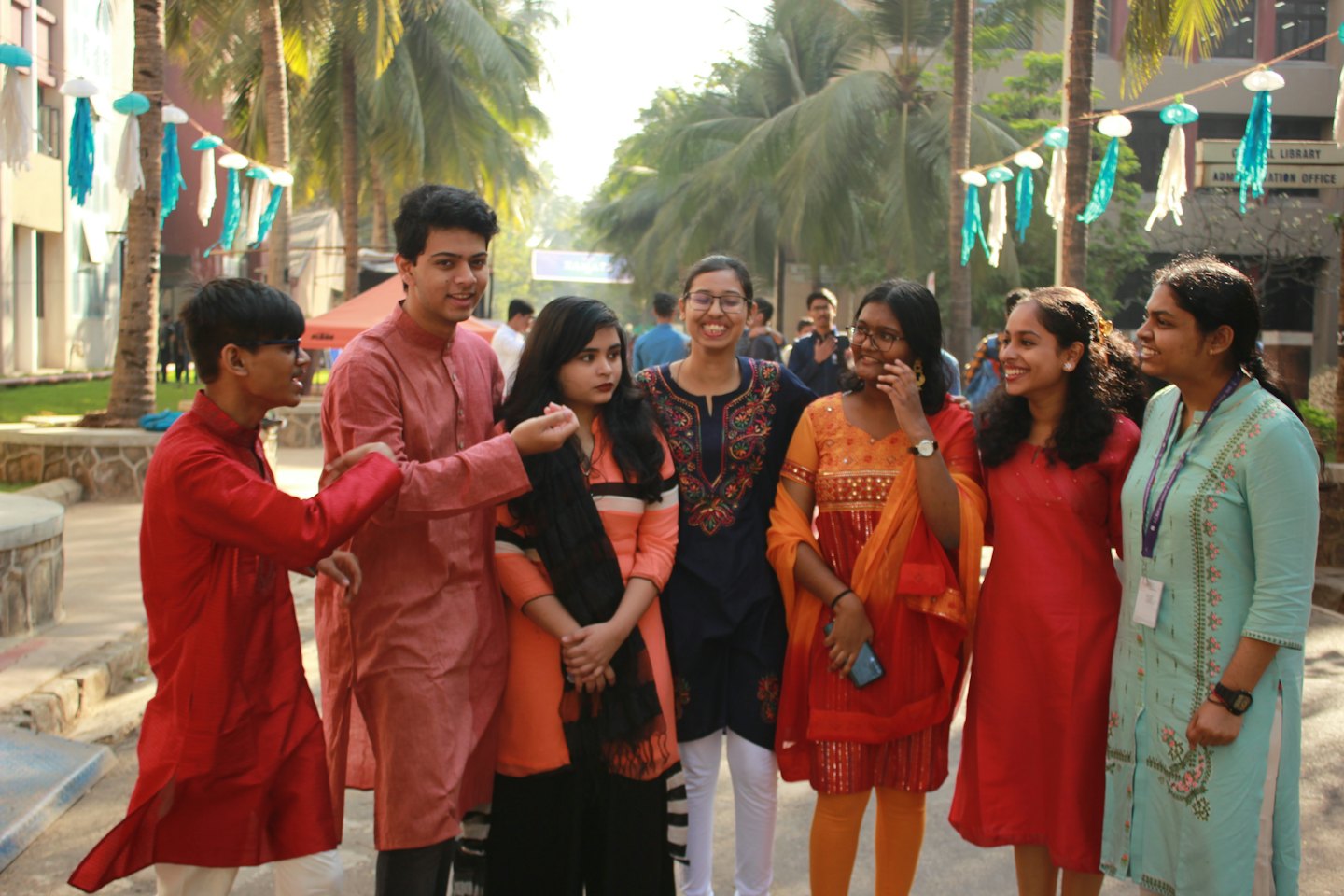 Six adults in traditional attire talk together on a decorated patio.