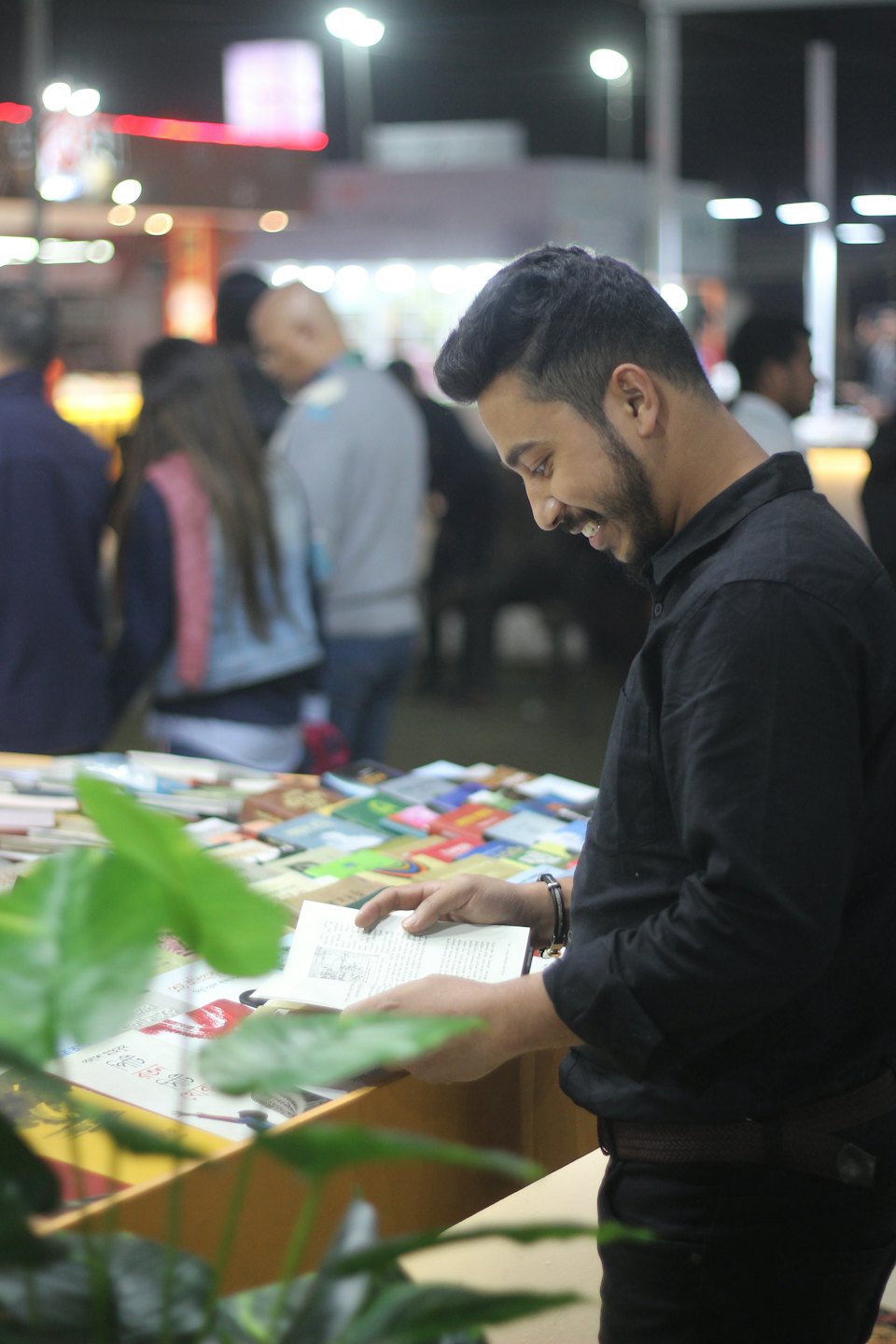 Man smiling while reading a book at a book fair.